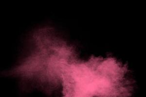 Pink dust particles splash on black background.Pink powder splash. photo