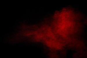 Red powder explosion on black background. Freeze motion of red dust particles splash. photo