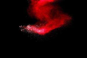 Red powder explosion cloud on black background. Freeze motion of red color dust  particles splashing. photo