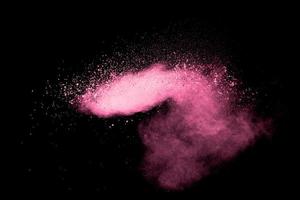 Pink dust particles splash on black background.Pink powder splash. photo