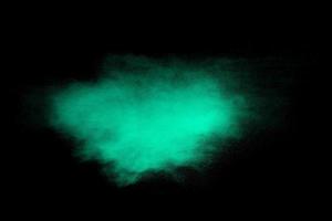 Green dust particles explosion on black background. Color powder dust splash. photo