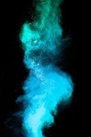 Launched blue dust particles splashing.Bizarre forms of blue powder explosion cloud on white background. photo