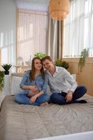 Pregnant couple hugging while sitting on the bed photo