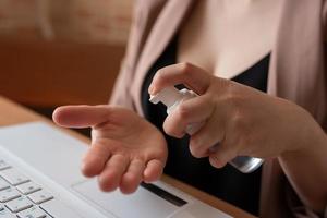 A female freelancer rubs her hands with a hand sanitizer. photo