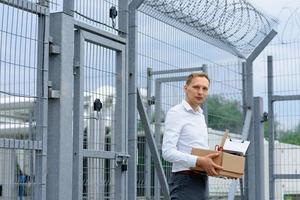 The businessman got out of prison with his things and is thinking about what to do next. A man stands near the exit from the prison. photo