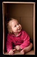 Little cute, beautiful girl sits in a box. photo