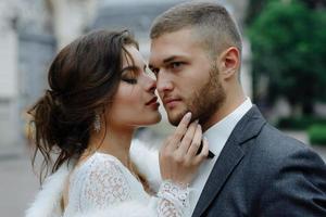 the groom in a gray suit and the bride in a gray dress look at each other, closeup portrait photo