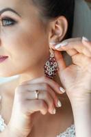 Young beautiful bride shows her earrings. Focus on jewelry. photo
