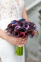The bride holds a bouquet of dark purple callas. photo