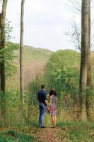 joven pareja hermosa enamorada en el bosque. una pareja se abraza cerca de un barranco entre los árboles. espacio libre. foto