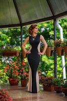 Young beautiful woman in a dress posing on the terrace against the background of home flowers. photo