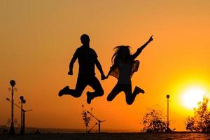 couple jumping in sunset photo