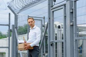 The businessman got out of prison with his things and is thinking about what to do next. A man stands near the exit from the prison. photo