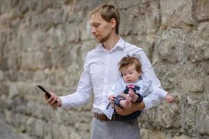 A young father is talking on a cell phone and holds his little daughter in his arms. copy space photo