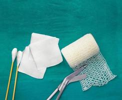 tools include scissors, swabs,net roll gauze and blood gauze on green surgical dress  for clean wound photo