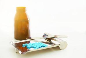 pills counting tray with spatula and round coated medicine tablets and jar on blur background with copy space photo