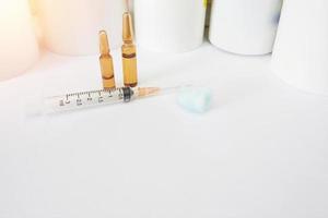 Medical syringe ,cotton ball and ampules on drugstore bottles background in self drug intake buying concept photo