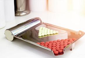 Red and green pills on counting tray on pharmacy counter photo