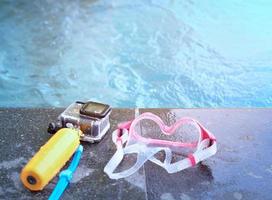 cámara de acción con estuche impermeable y palo flotante y googles en la piscina de la piscina en un niño borroso en el fondo del agua en el concepto de vacaciones de verano en la playa