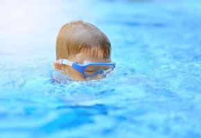 Kid head with goggles in diving down from surface into under water in the sea