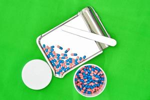 blue capsules on tray with jar in pharmacy shop on green background photo