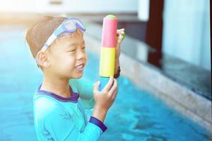 Boy play water gun with goggles in hotel vacation concept photo