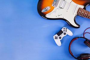 Electric guitar, joystick, headphones. Pop culture media attributes. Top view. photo