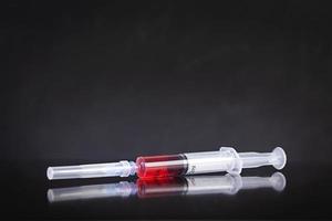 Single use syringe and vaccine on dark background photo