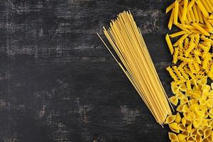 Different dry pasta on a wooden background. Top view photo