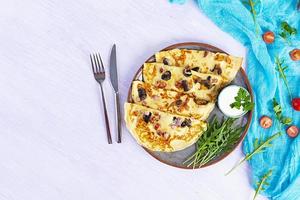 Delicious pancakes with mushrooms, ham and cheese, arugula, tomatoes and sour cream on a wooden background photo