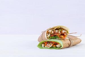 Delicious shawarma sandwich with chicken on wooden background photo