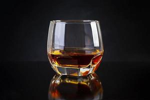 Glass of whiskey on dark background. photo