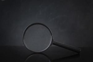 Search concept. Magnifying glass on dark background photo