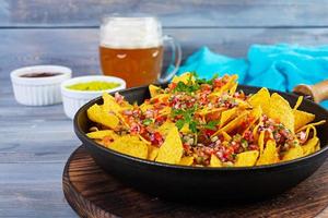 Mexican nachos with cheese. Corn chips with guacamole, salsa and tomato ketchup. photo