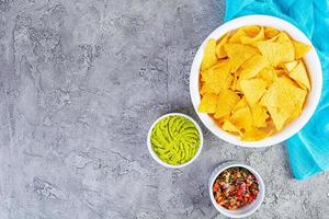 Mexican nachos with cheese. Corn chips with guacamole, salsa and tomato ketchup. photo