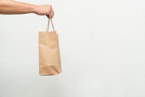 Hand with Kraft paper bag isolated on white background. save the world, reduce global warming photo