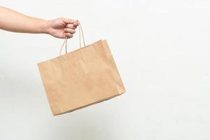 Hand with Kraft paper bag isolated on white background. save the world, reduce global warming photo