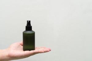 Green cosmetic bottle with label isolated on white background. Close up aroma spray bottle. Concept of organic cruelty free. Natural organic spa cosmetics concept. photo