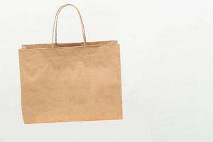 Hand with Kraft paper bag isolated on white background. save the world, reduce global warming photo