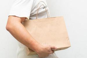 Hand with Kraft paper bag isolated on white background. save the world, reduce global warming photo