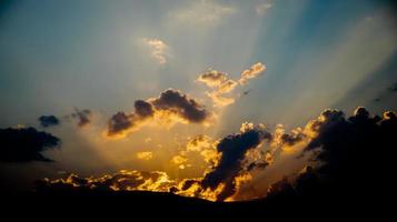 un rayo de sol se abre paso a través de la montaña y las nubes en el cielo azul, el crecimiento de la esperanza y el comienzo. foto