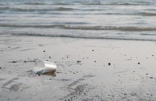 una basura de vidrio plástico desechada en la playa por la noche. foto