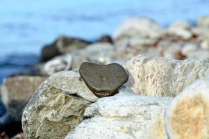 Heart shape stone against background of beach. Summer sunny day. Love, wedding and Valentine day concept. Finding beautiful and interesting stones. Beach vacation photo