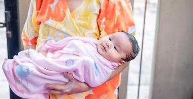 Asian mom shower baby to clean dirt give child in bath container for cleanliness lifestyle family between mother and child Used for baby shower cream products shampoos lotions and baby care product photo