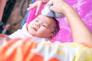 mamá asiática ducha al bebé para limpiar la suciedad dar al niño en un recipiente de baño para la limpieza estilo de vida familiar entre la madre y el niño utilizado para la ducha del bebé productos de crema champús lociones y productos para el cuidado del bebé foto