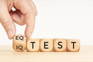 Hand flipping a wooden block with eq test and iq test phase. Copy space. White background photo