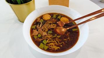 Boat noodles Thai style noodle soup or noodles with pork and pork balls on the white table photo