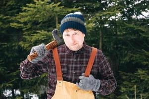 Portrait of a man lumberjack with an ax in his hands on a background of forest and trees photo