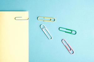 Colorful paper clips on bright blue and yellow background. Minimalist concept flat lay. photo