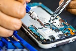 Technician repairing inside of mobile phone by soldering iron. Integrated Circuit. the concept of data, hardware, technology. photo